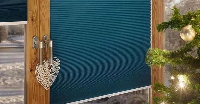 Türkises Plissee an einem Fenster mit Weihnachtsdekoration